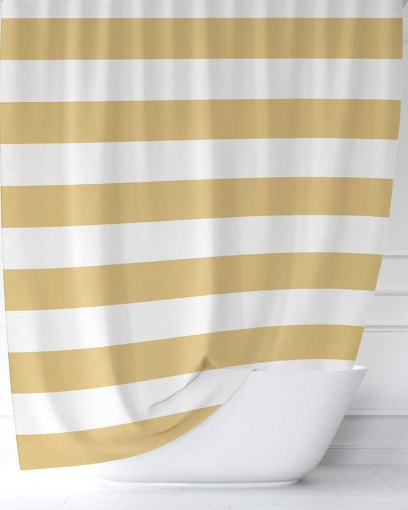 A gold and white striped shower curtain hangs in a bathroom, partially obscuring a white bathtub.