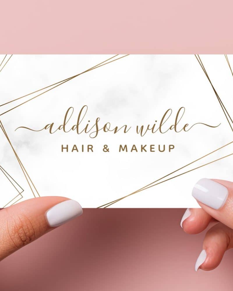 A white business card with gold geometric lines and marble texture. The name Addison Wilde Hair & Makeup is written in elegant script.