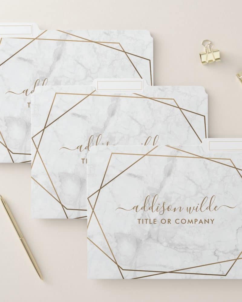 Three file folders with a marble and gold geometric design. The bottom folder is labeled with a name and title.