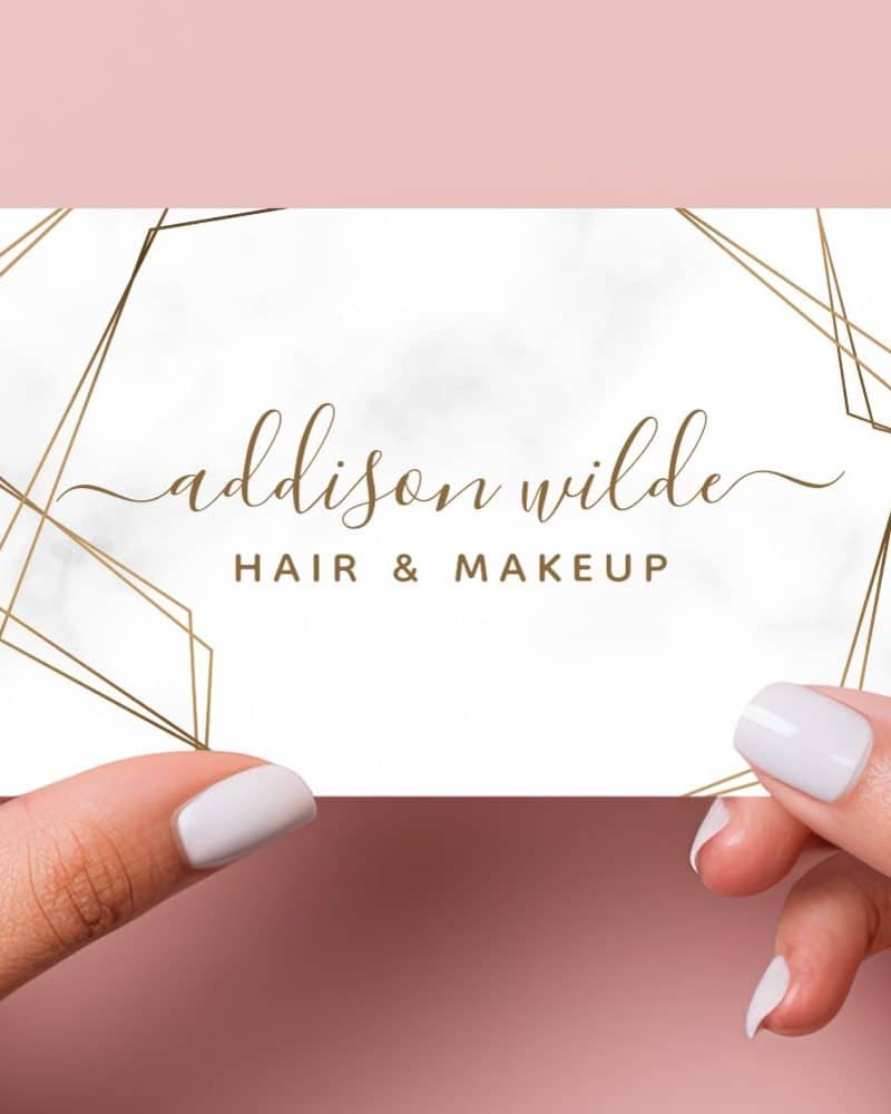 A business card for Addison Wilde Hair & Makeup, featuring a marble background and gold geometric lines.