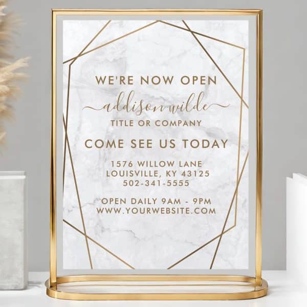 Gold-Framed Sign Announcing Addison Wilde'S Grand Opening, Including Address And Hours.