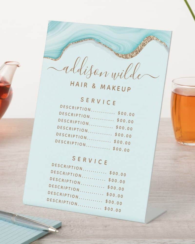 A light blue and gold hair and makeup price list stand with the name Addison Wilde.