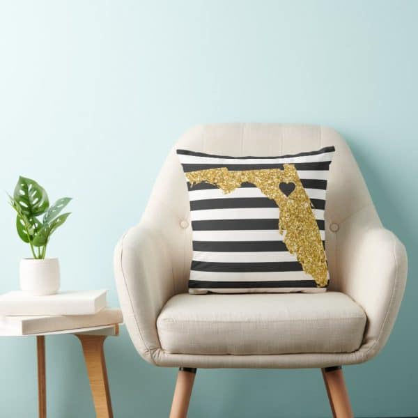 Gold Glitter Florida Shaped Pillow On Black And White Striped Fabric.