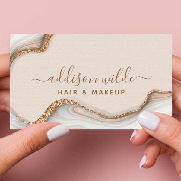 A Beige Business Card With Gold Glitter Accents And A Stylized Agate Design Features The Name Addison Wilde, Hair &Amp; Makeup.