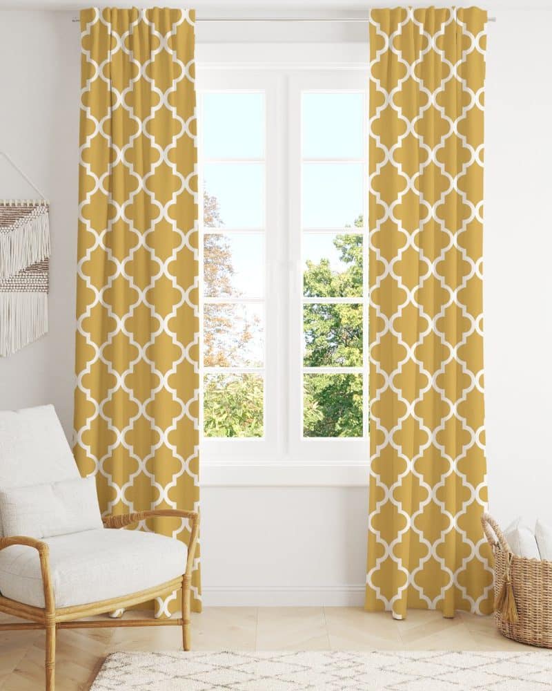 Mustard yellow curtains with a white quatrefoil pattern hang in front of a window.