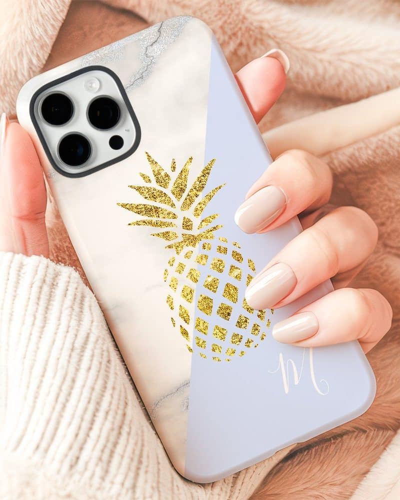 Hand holding a phone case with a gold pineapple design.