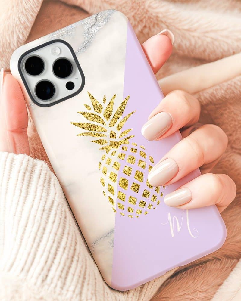 A hand holding a phone case featuring a gold glitter pineapple design on a marble and lavender background.