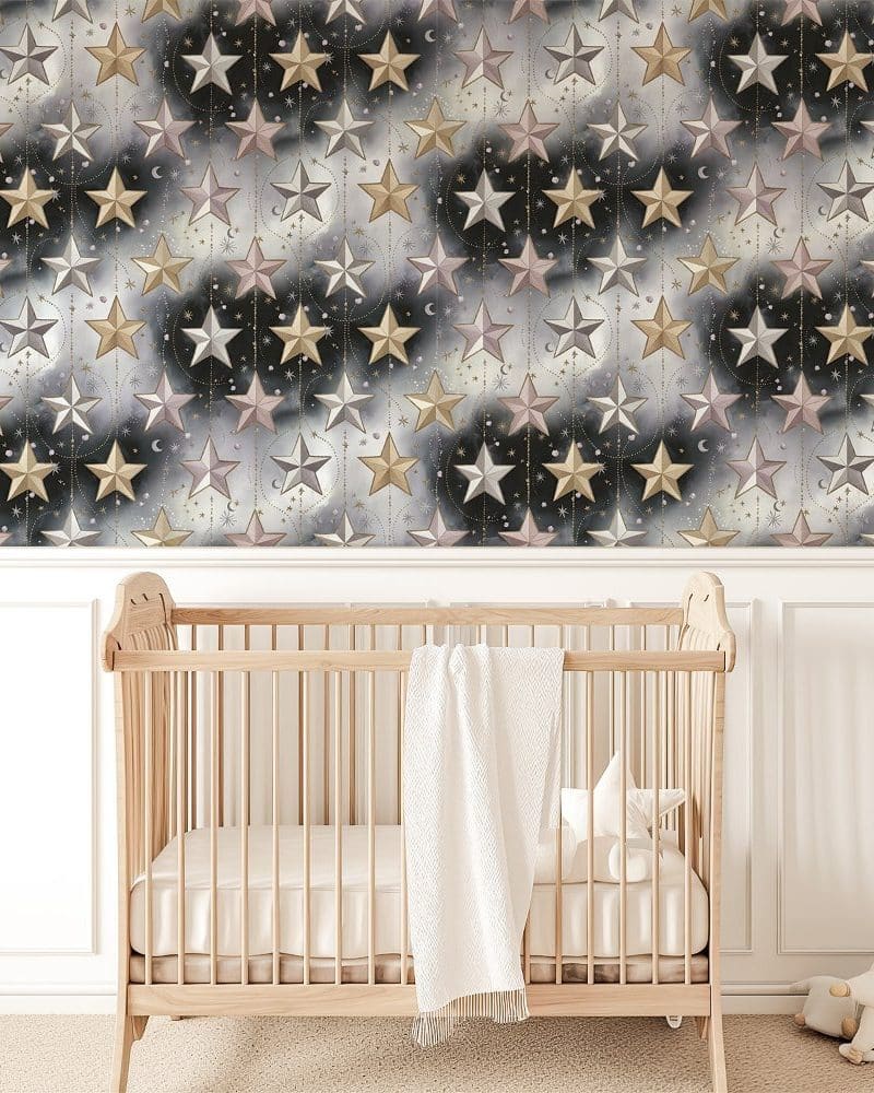 A crib sits in front of a wall covered in a celestial-themed wallpaper featuring gold, pink, and silver stars on a dark background.