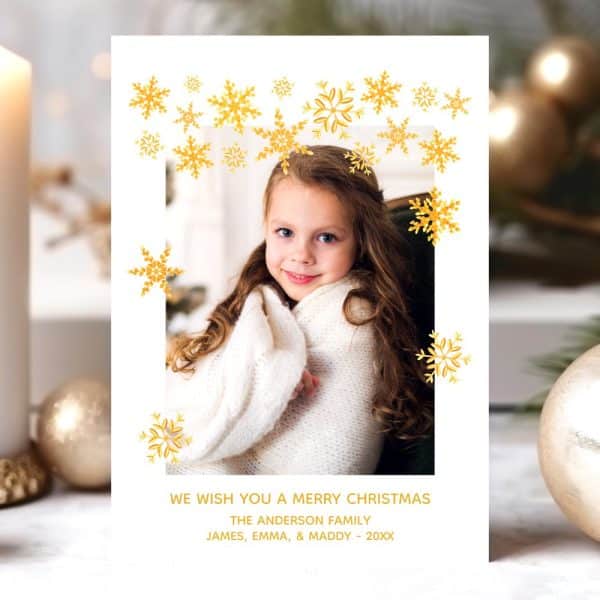 Christmas Card Featuring A Young Girl Wrapped In A White Blanket, Surrounded By Gold Snowflakes.