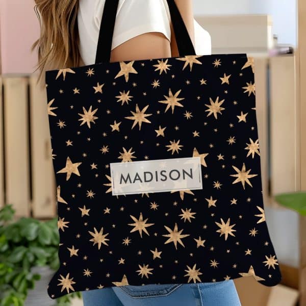 Personalized Tote Bag With Gold Stars On A Black Background. The Name Madison Is Printed On The Bag.