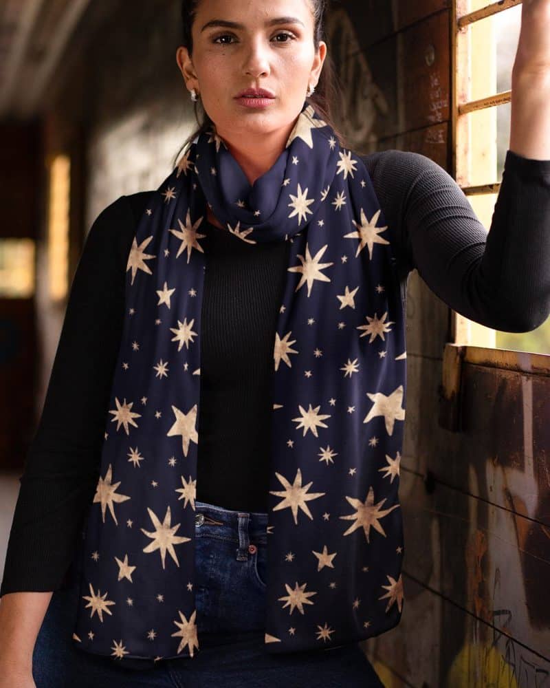 Woman wearing a navy blue scarf with a gold star pattern.