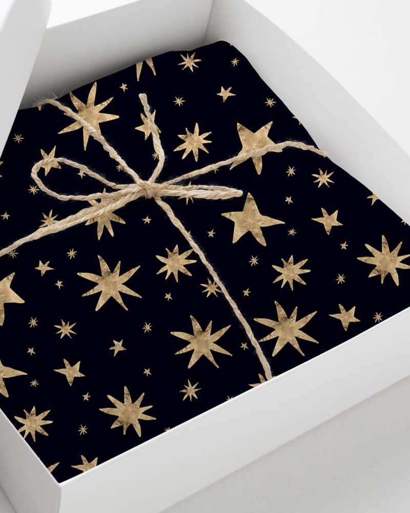 A gift wrapped in dark blue paper with a gold star pattern, tied with twine.