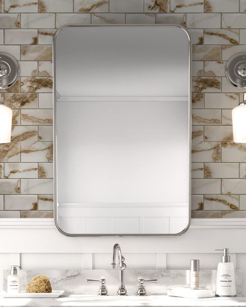 Bathroom vanity with a rectangular mirror flanked by wall-mounted lights and a marble-look backsplash.