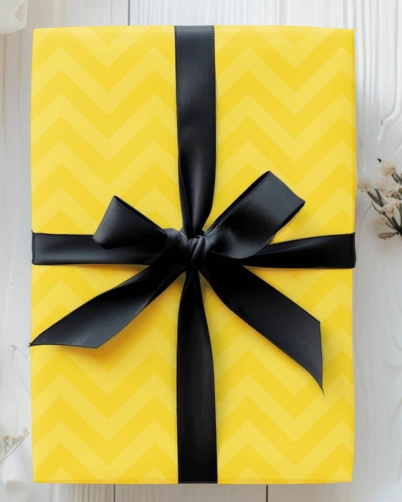 Yellow gift box with black ribbon bow.