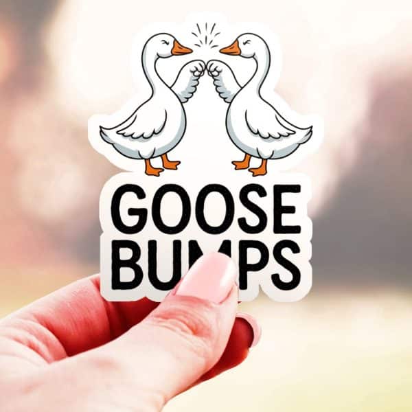 A Hand Holds Up A Sticker Showing Two Geese Fist-Bumping, With The Text Goosebumps Below.