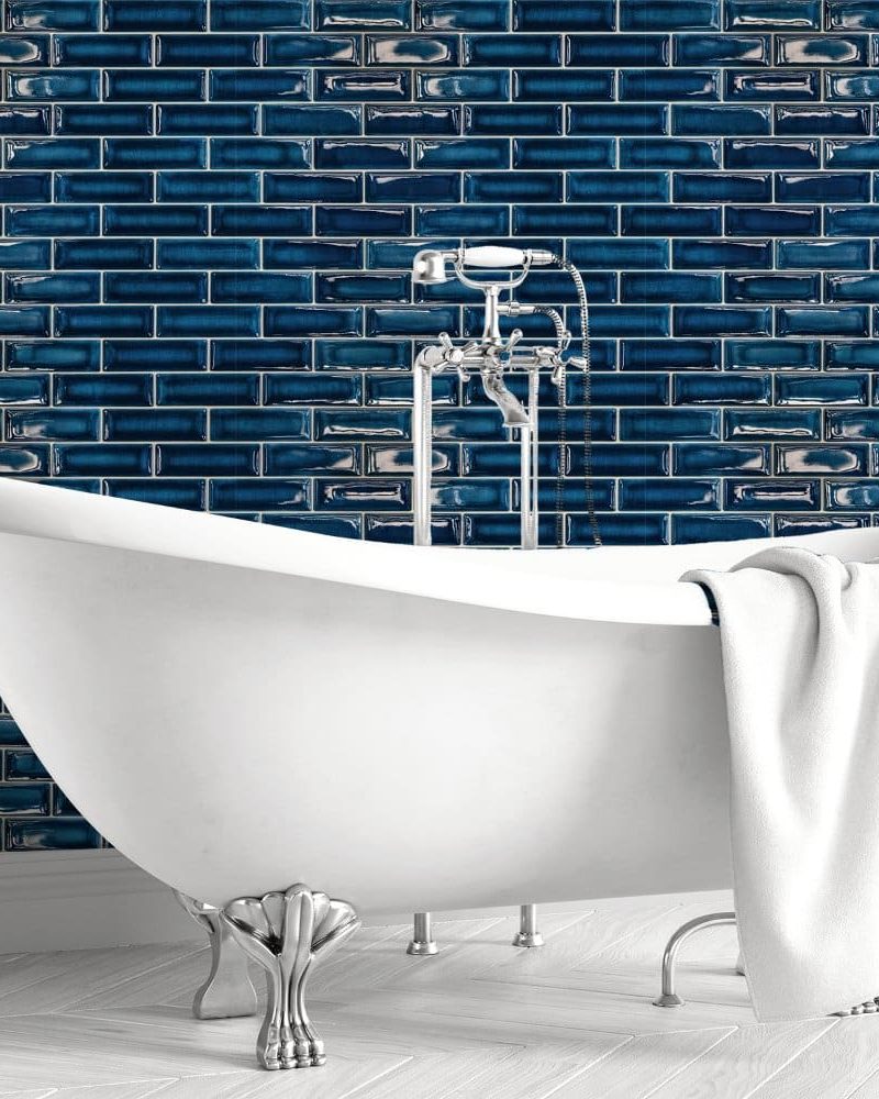 White clawfoot bathtub against a dark blue tiled wall.