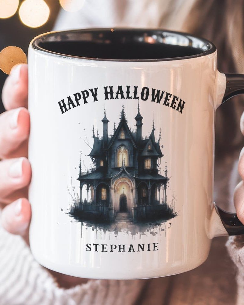 A white Halloween mug with a black handle, featuring a spooky house illustration and personalized name, Stephanie.