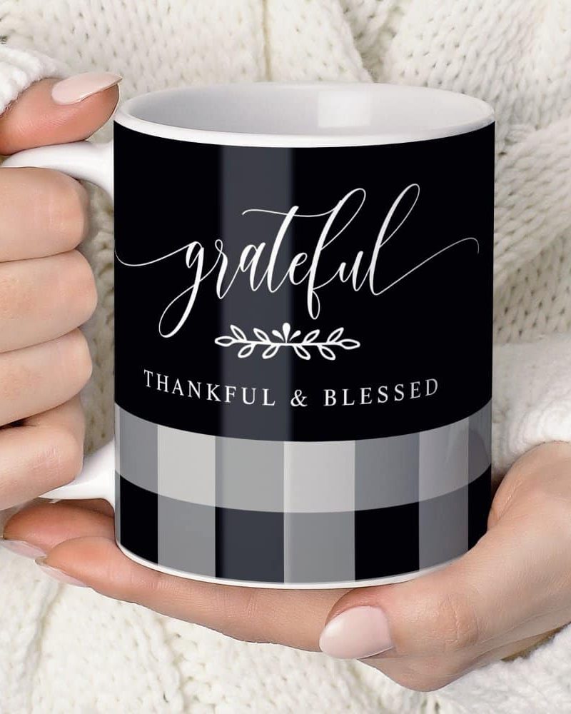 A person's hands hold a black and gray plaid coffee mug. The mug says grateful, thankful & blessed in elegant script.