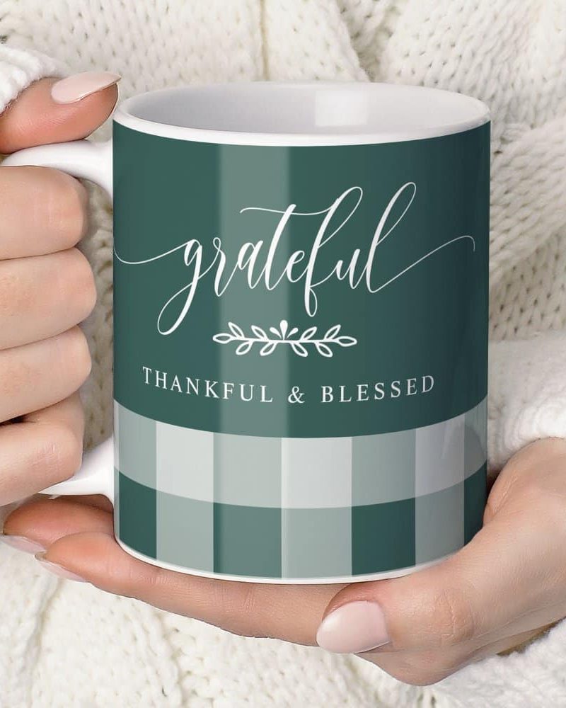 A person holds a teal mug with the word grateful in elegant script. Below it, the words Thankful & Blessed are printed. A subtle gingham pattern is visible at the bottom.