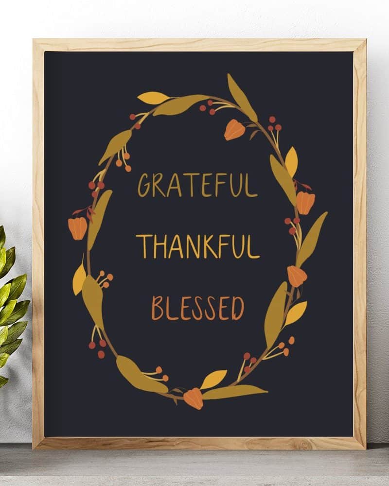 Framed print with a dark background featuring a fall-themed floral wreath surrounding the words grateful, thankful, and blessed.