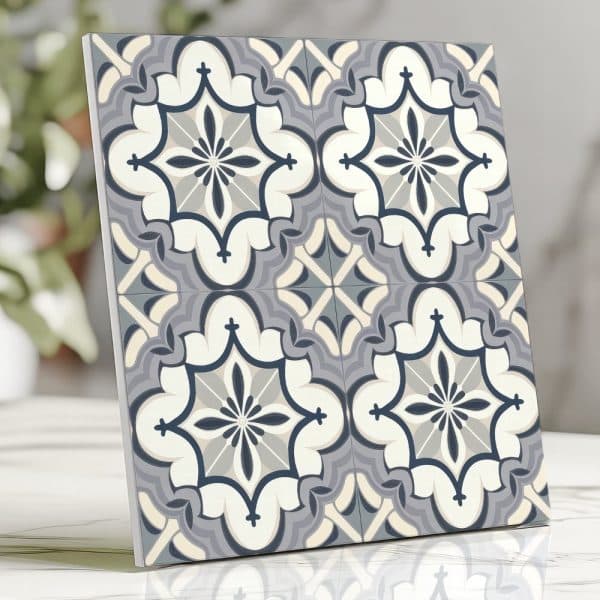 A Square Tile With A Repeating Ornate Pattern In Shades Of Gray, Blue, And Off-White.
