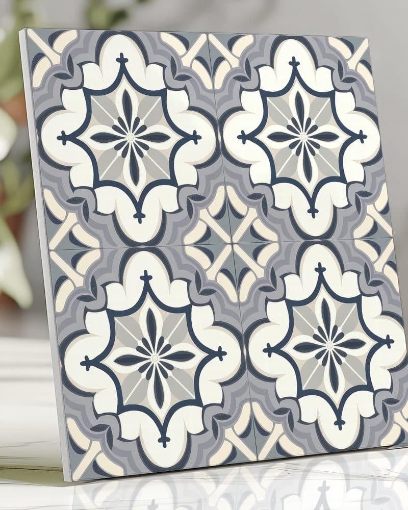A square tile with a repeating ornate pattern in shades of gray, blue, and off-white.