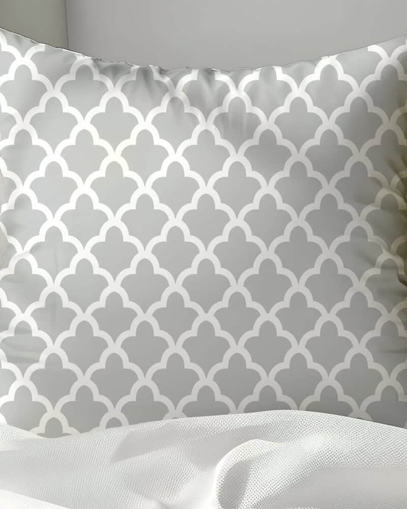 Gray throw pillow with a repeating white geometric pattern.