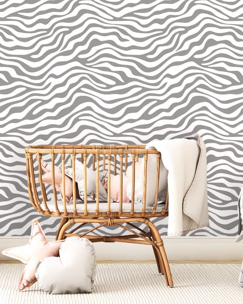 Baby in a wicker bassinet against a gray and white zebra-striped wall.
