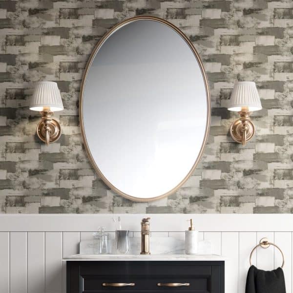 Oval Mirror Flanked By Wall Sconces Above A Bathroom Vanity.
