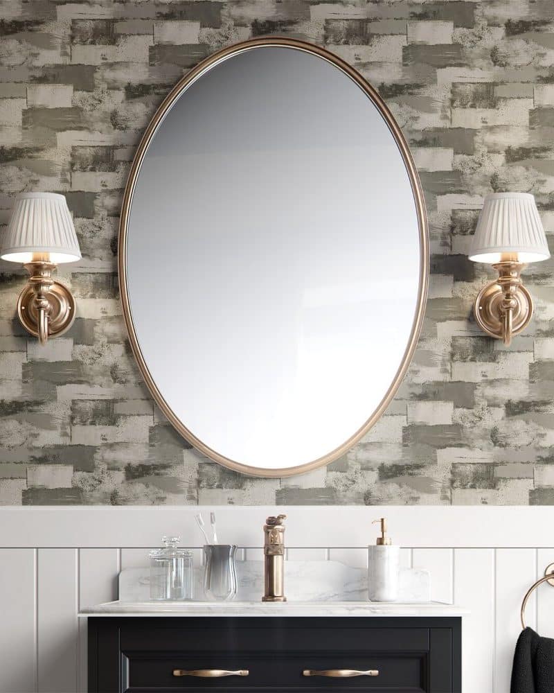 Oval mirror flanked by wall sconces above a bathroom vanity.