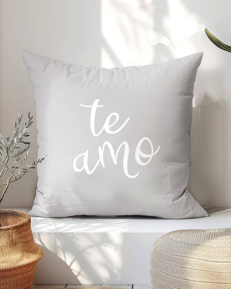 Light gray throw pillow with the words te amo in white script.