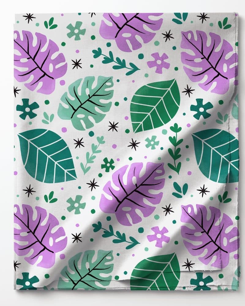 Folded fabric with a pattern of purple and green leaves and small flowers.