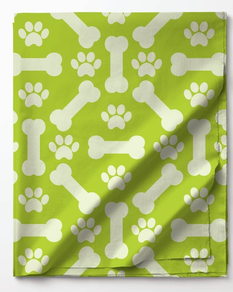 Lime green fabric with a repeating pattern of white bones and paw prints.