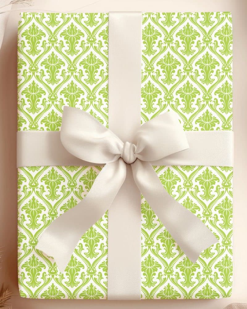 A lime green and white damask patterned gift box with a large off-white bow.