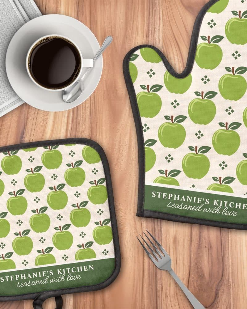 A kitchen oven mitt and pot holder with a green apple pattern and personalized text.