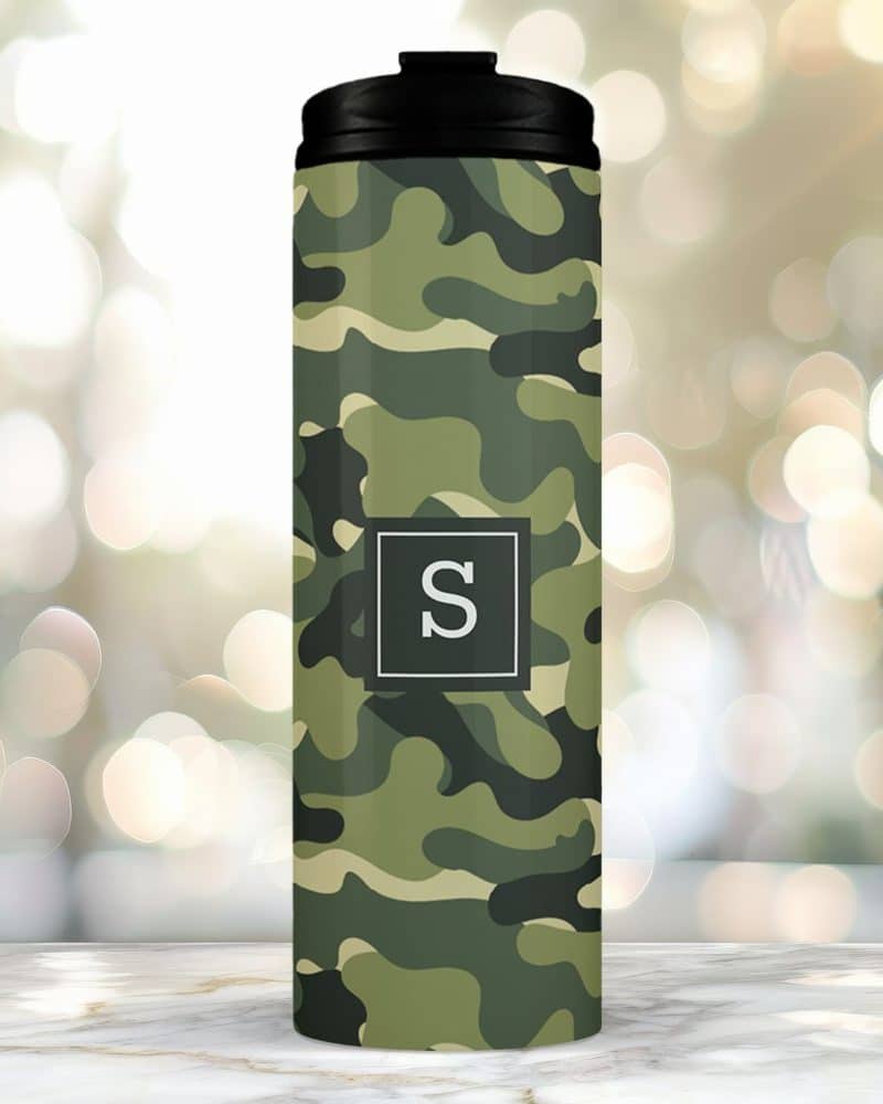 Camouflage travel tumbler with a black lid and the letter S in a gray square.