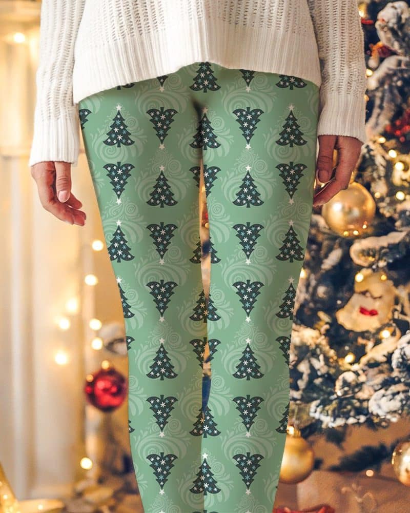 Green leggings with a repeating pattern of dark green Christmas trees and snowflakes.