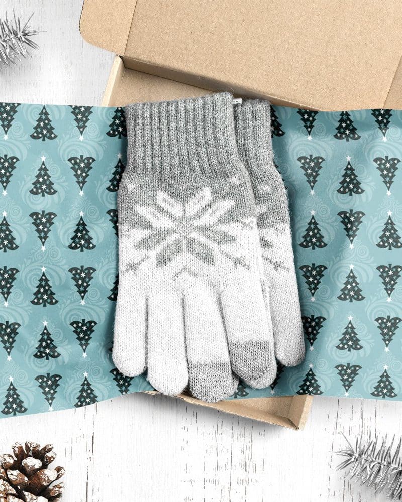 Pair of gray and white knit gloves with snowflake pattern, in a Christmas-themed gift box.