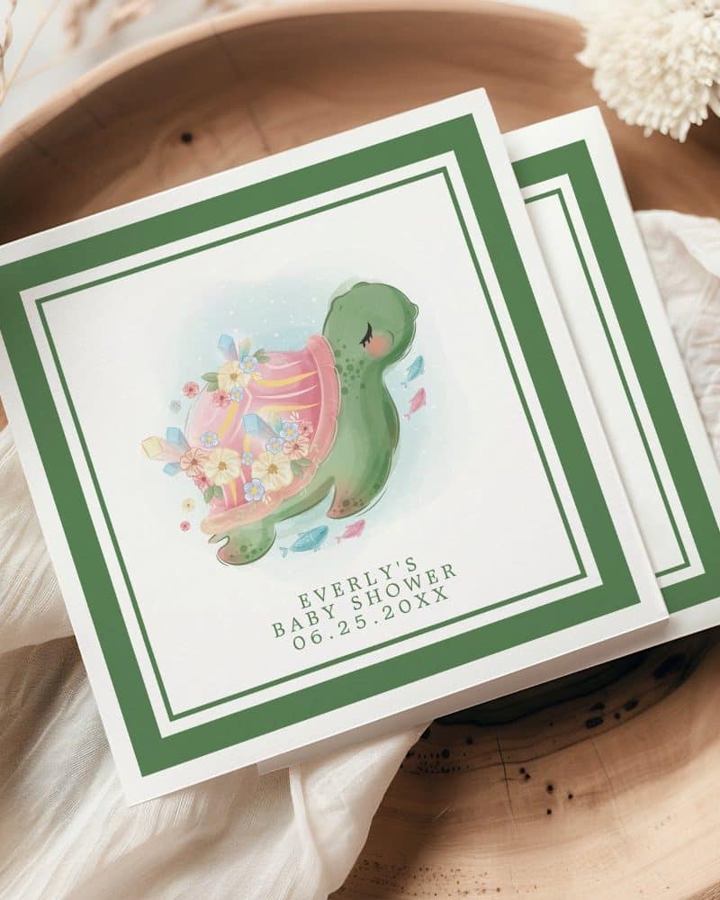 Baby shower invitation featuring a watercolor illustration of a turtle adorned with flowers and crystals.