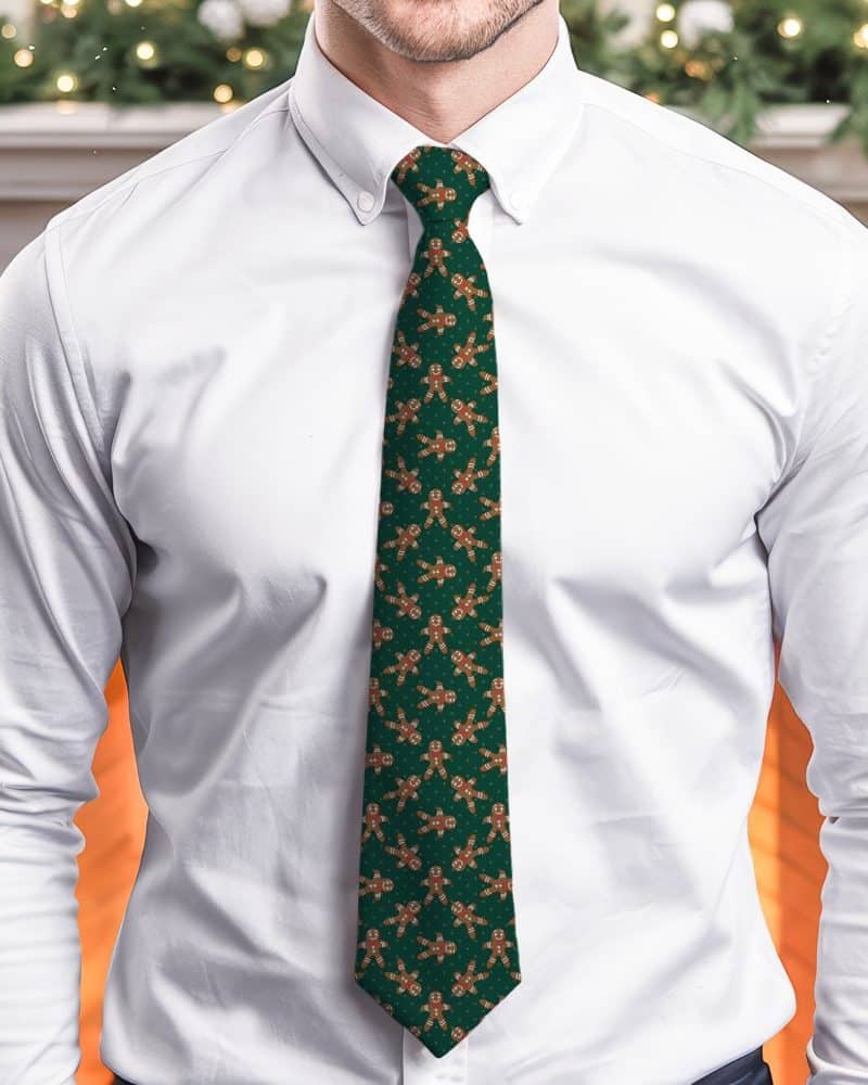 A man wearing a dark green tie with a repeating pattern of gingerbread men.