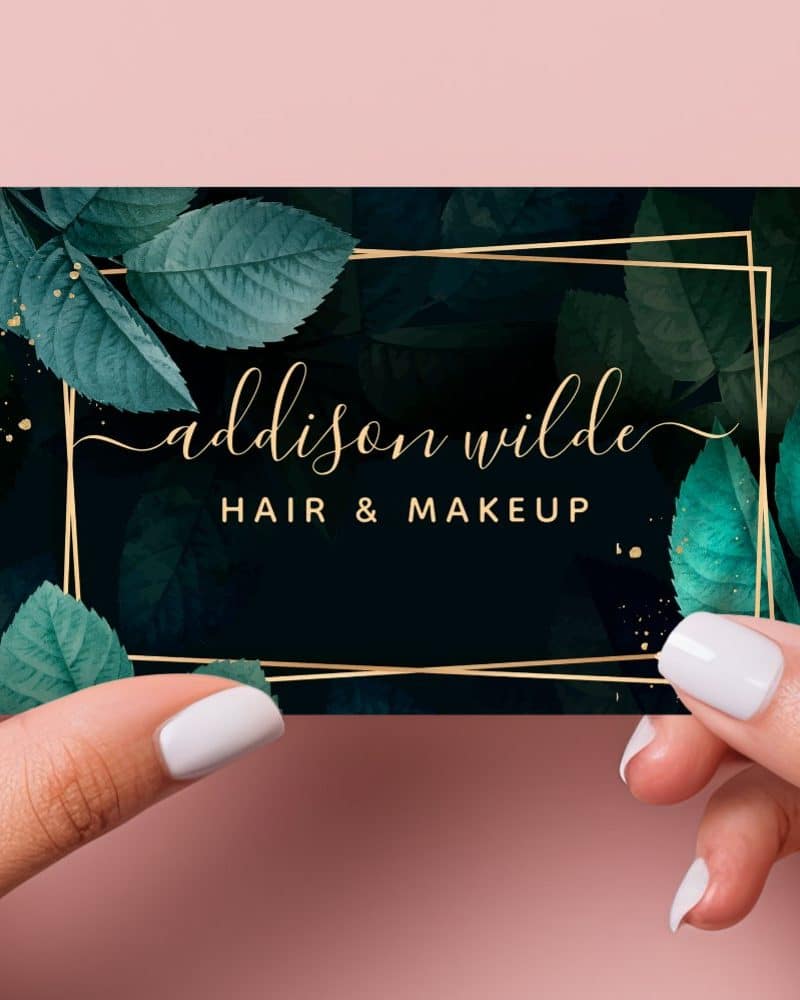 A dark teal and gold business card for Addison Wilde Hair & Makeup, featuring a gold frame and leaf design.