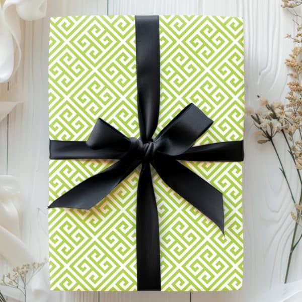 A Lime Green Gift Box With A Black Ribbon. The Box Is Wrapped In Paper With A Geometric Pattern.