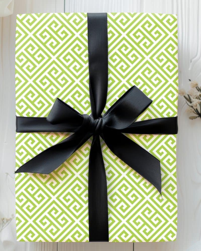 A lime green gift box with a black ribbon. The box is wrapped in paper with a geometric pattern.