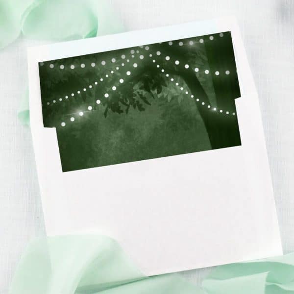White Envelope With A Dark Green Liner Featuring String Lights Draped On A Tree.