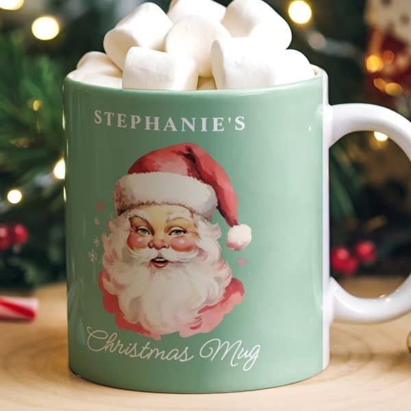 A Teal Christmas Mug With Stephanie'S Name, A Vintage Santa Image, And The Words Christmas Mug. The Mug Is Filled With Marshmallows.