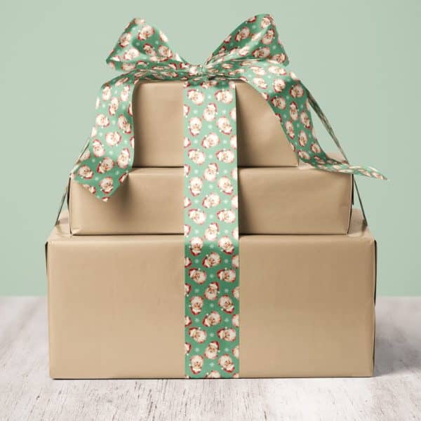 Stack Of Three Brown Wrapped Gifts Tied With A Green Ribbon Featuring A Santa Claus Pattern.