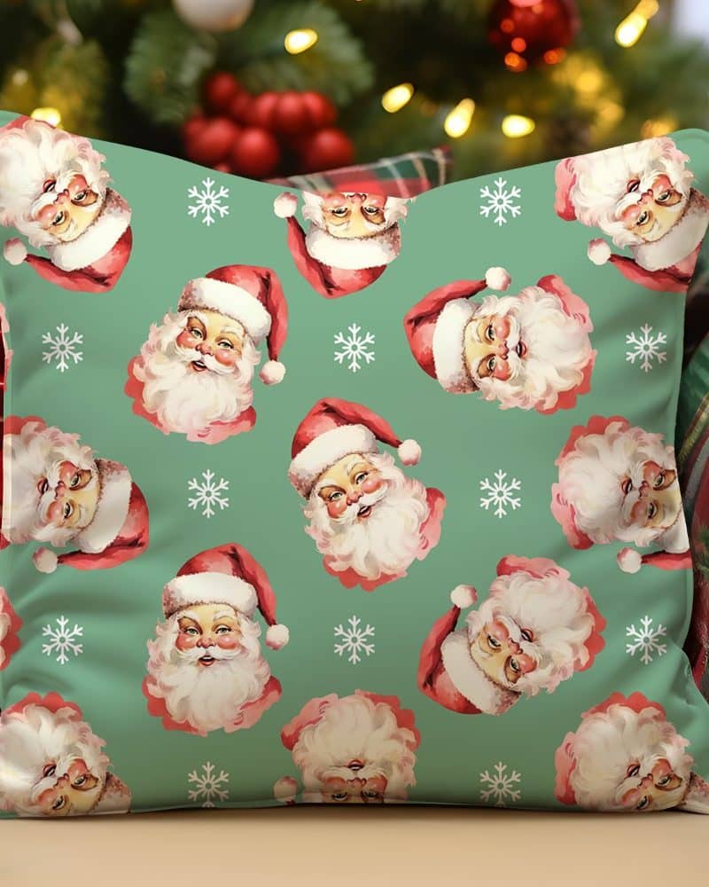 Green throw pillow with a repeating pattern of vintage Santa Claus faces and snowflakes.