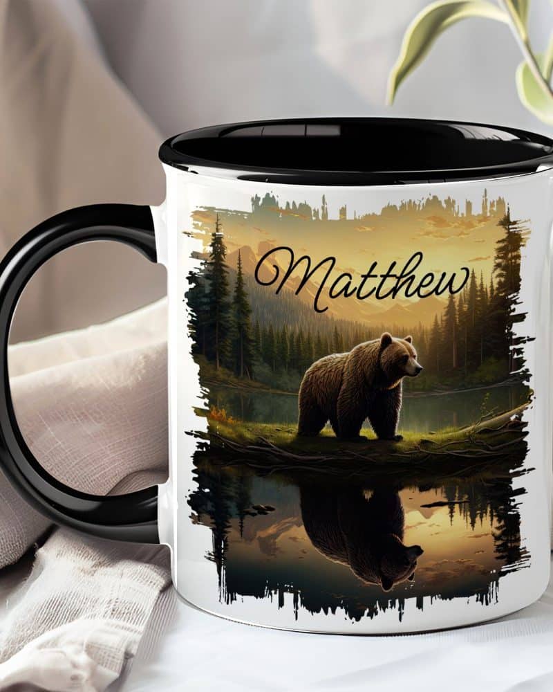 Personalized coffee mug with a grizzly bear reflected in a lake at sunset. The name Matthew is printed on the mug.