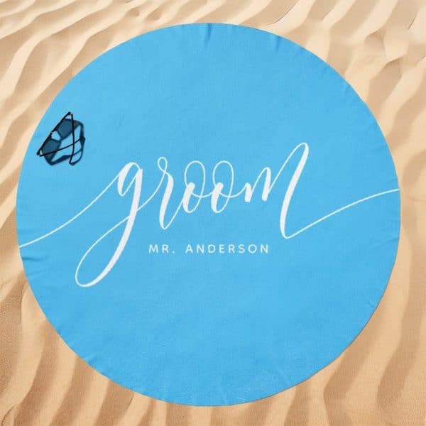 Light Blue Round Beach Towel With The Word Groom And Mr. Anderson In White Script.