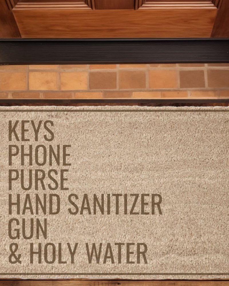 Tan doormat with the words keys, phone, purse, hand sanitizer, gun, and holy water.
